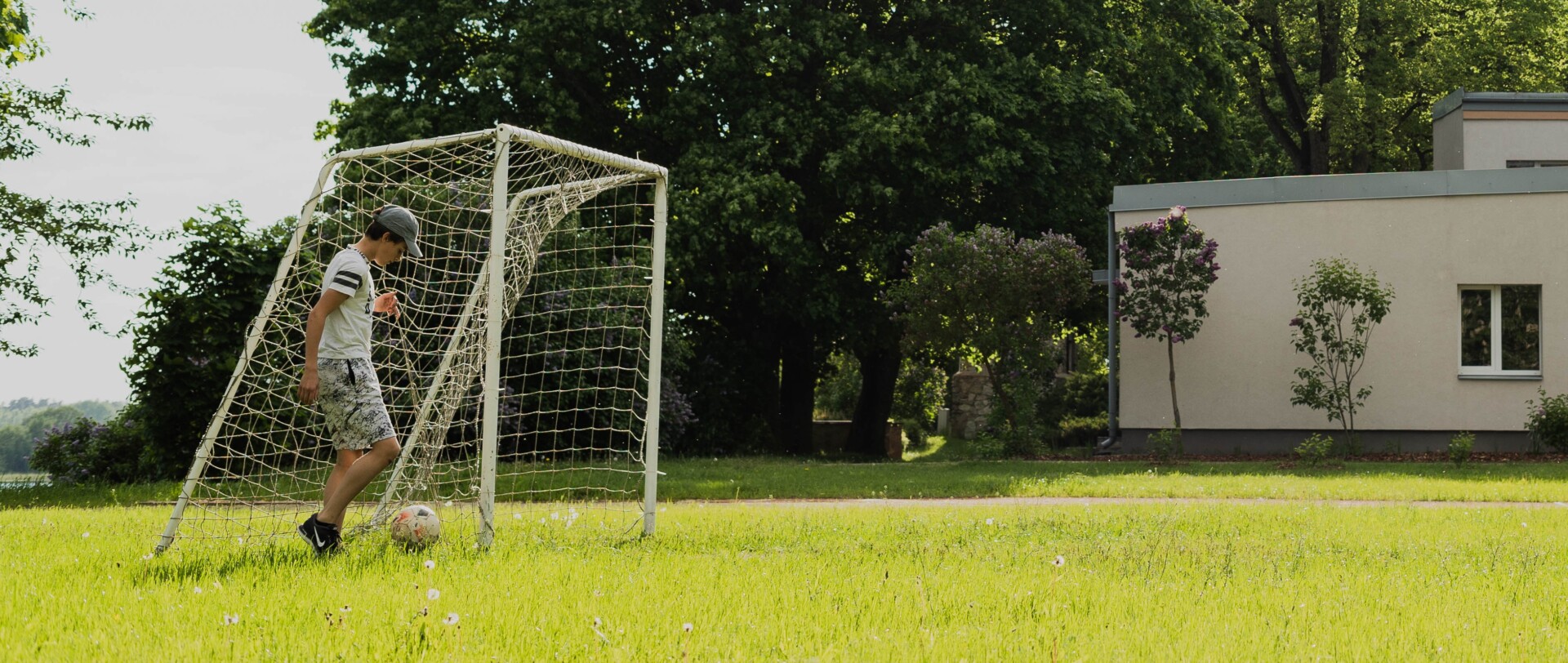 Zēns spēlē bumbu ārā pie furbola vārtiem